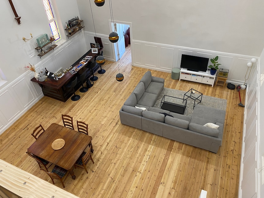 A birds eye view of a room, with a table, bar, couch and television. 