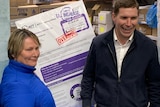 Alistair Coe and Nicole Lawder stand in a commercial freezer with a print out of a giant rates bill.