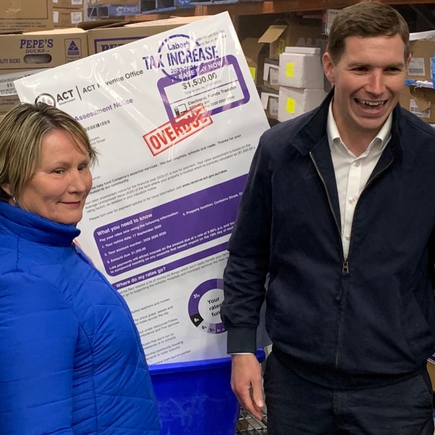 Alistair Coe and Nicole Lawder stand in a commercial freezer with a print out of a giant rates bill.