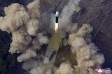 Aerial view of missile in air with smoke coming off the ground.