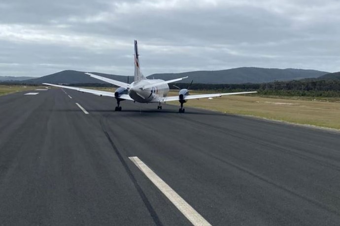 A plane stopped on a runway at an angle with a tyre mark on the runway leading up to it.