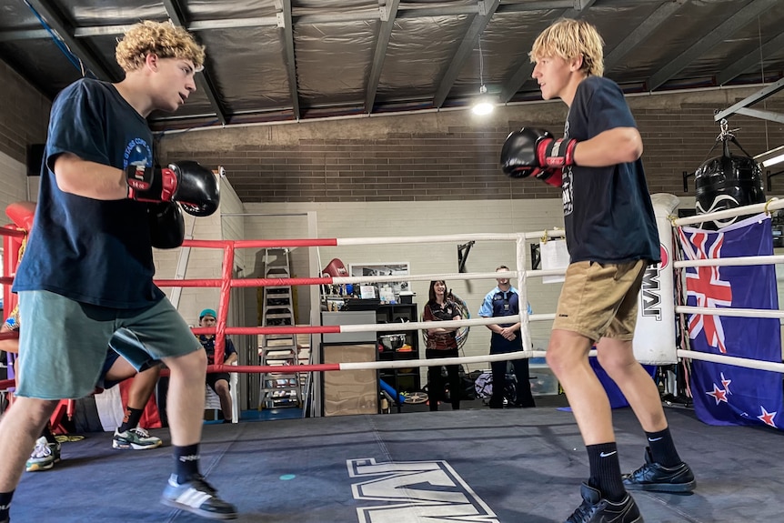 Two male teenagers sparring in a boxing ring