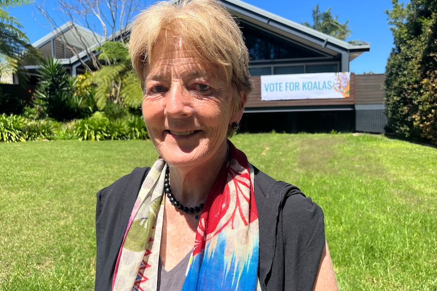 A smiling woman in the sun wearing a bright, multi-coloured scarf.