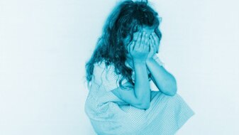 Young girl sitting in a corner covering her face with her hands (Thinkstock: Stockbyte)