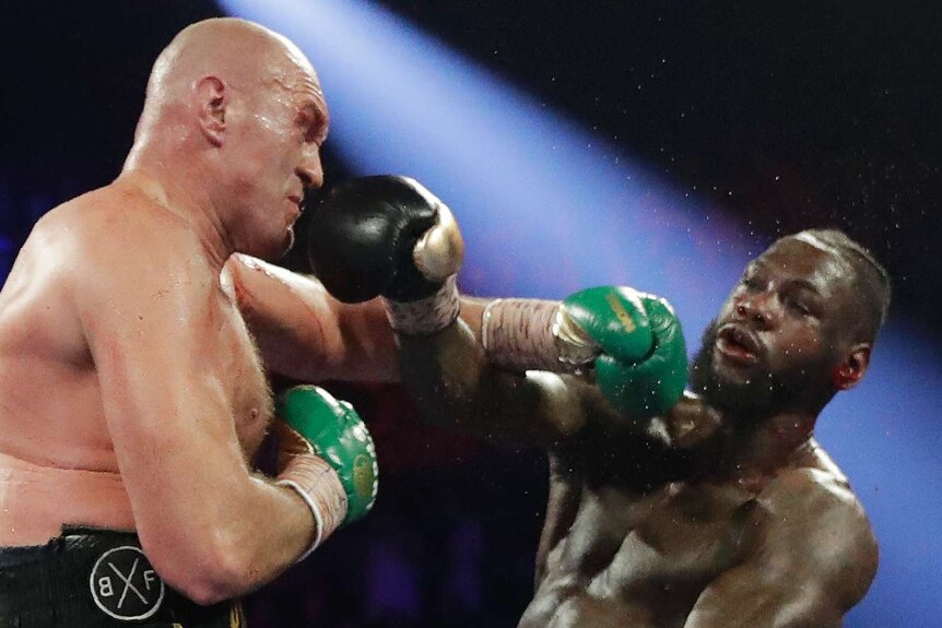 Deontay Wilder falls back as he is hit by Tyson Fury's left hook during their heavyweight title fight.