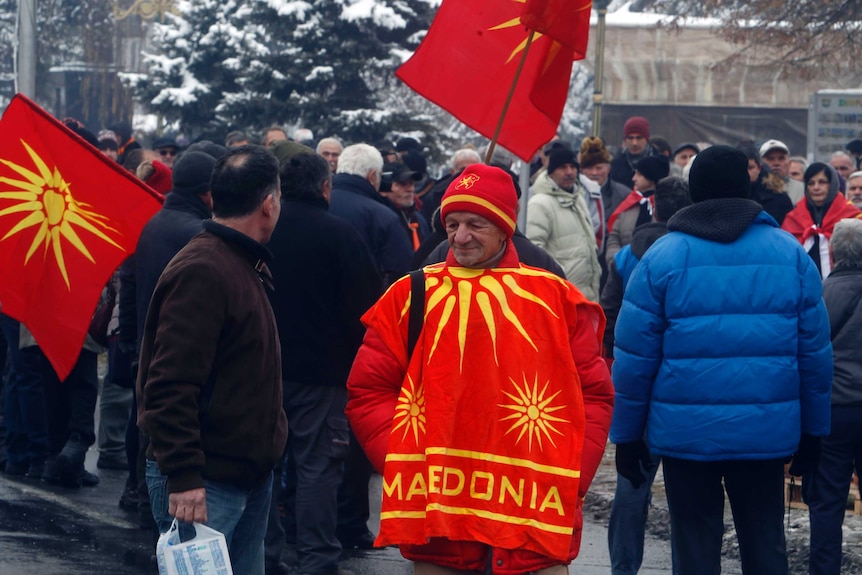 A group of protestors gather on a snowy street dressed in nationalist Macedonian attire.