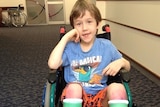 A young boy in a wheelchair with plaster casts on his lower legs
