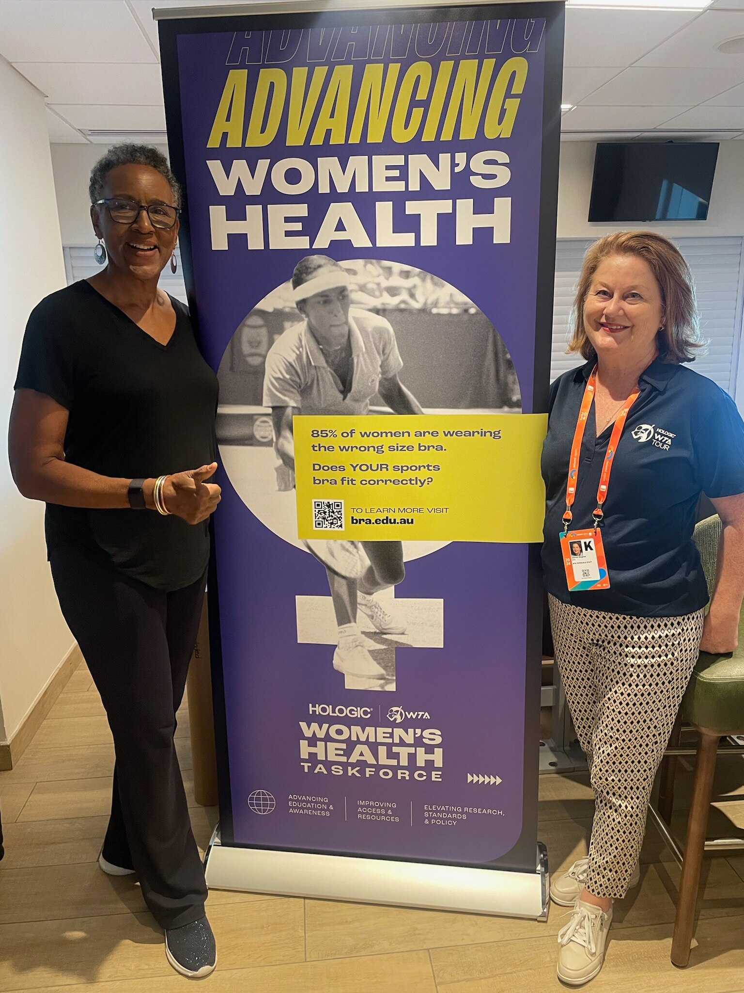 Deirdre and Leslie stand on either side of a women's health sign, smiling at the camera.