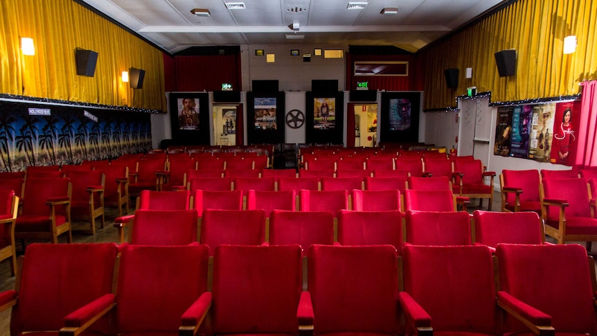 Rows of red cinema seats sit inside the timber building.