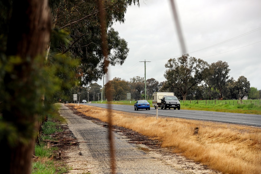 A car passes a four wheel drive with attached caravan on a country road