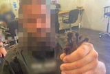 A man in a hair salon chair holds up dreadlocks that have been cut off.