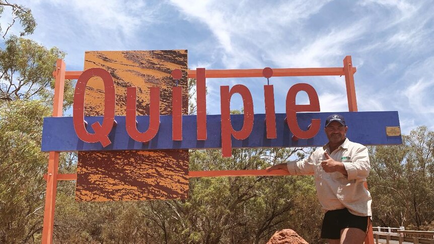 Brendan Farrell stands in front of sign for Quilpie, Queensland