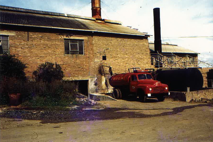 Old photo of red truck outside of brick and tin AJ Bush and Sons Bush's Protein Plant