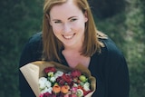 A photo taken from above of a young woman holding a bunch of flowers, smiling