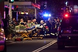 Paramedics stand with stretches near vehicles on a road.