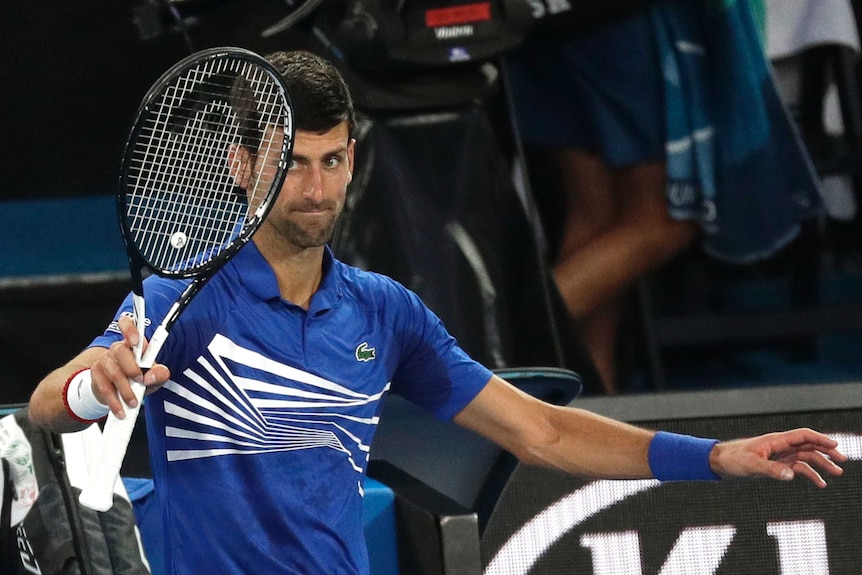 Novak Djokovic raises his racquet to the crowd after his match at the Australian Open.