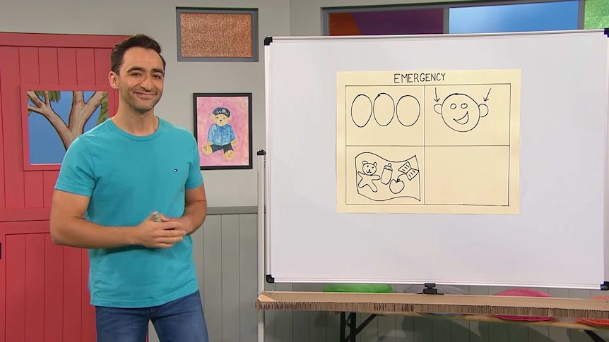 Matt standing next to a whiteboard with a sheet of paper with "Emergency" written on the top with a grid containing images.