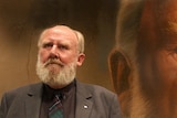 Bill Hunter standing in front of his portrait by Jason Benjamin for the Archibald.