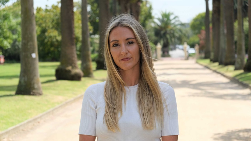 Keely Walsh looks into the camera with a garden backdrop.