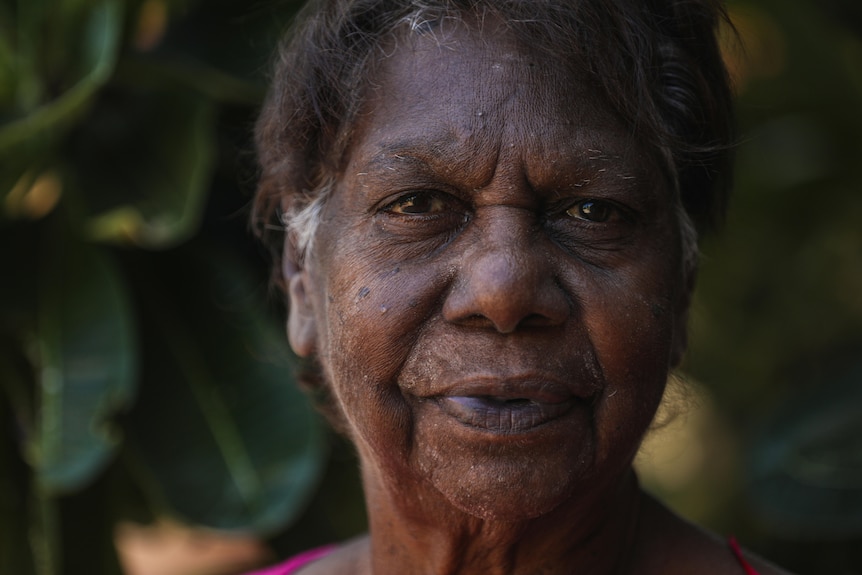 Aboriginal woman smiling at camera in front of tree