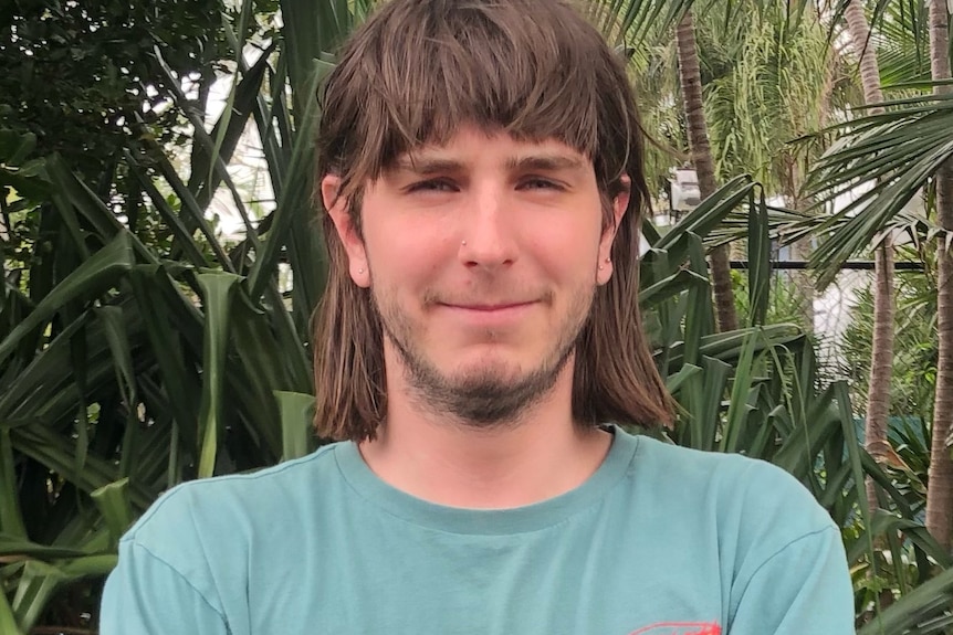 portrait shot of Zak Sezer wearing a green tee short and sporting a mullet hairstyle.