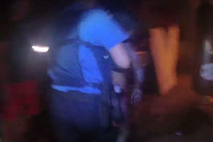 A grainy image of a police officer holding a boy with ash and smoke on his arms.