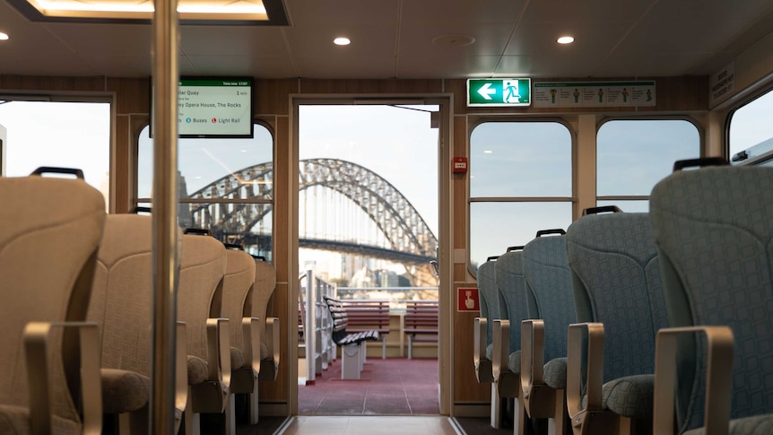 Empty rows of seats on either side of the aisle, the Sydney Harbour Bridge visible through the door