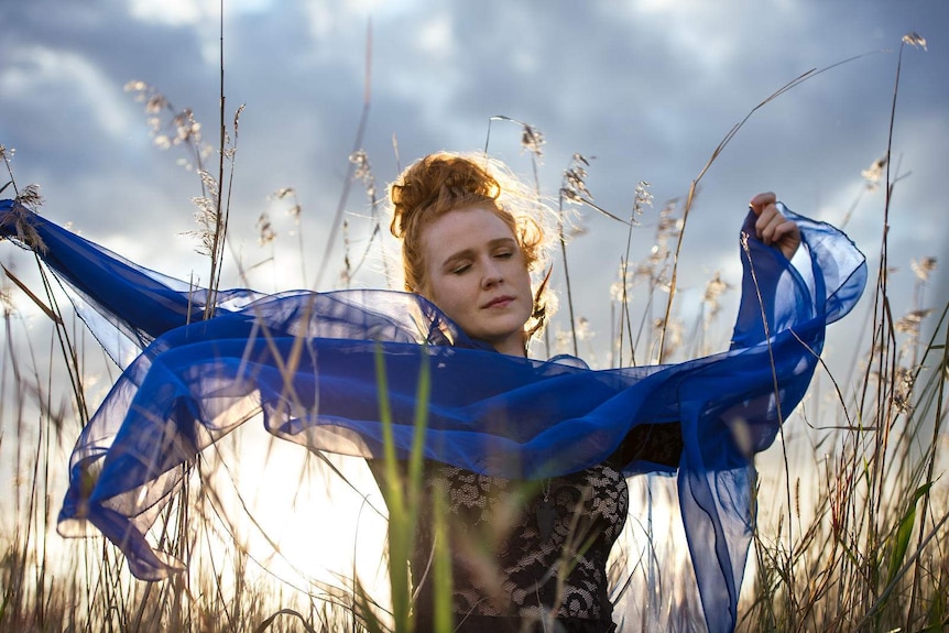 Claire Anne Taylor posing in grass with a flowing top