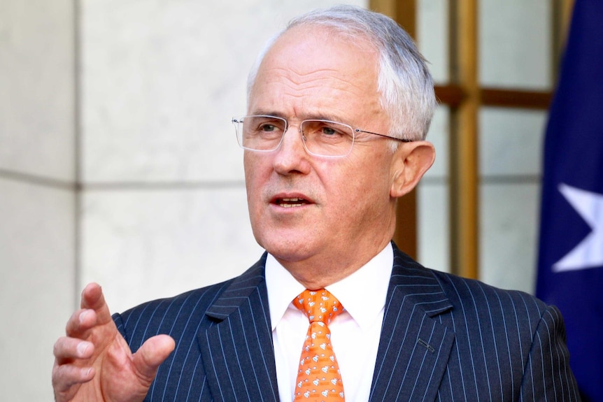 Upper body photo of Malcolm Turnbull gesturing as he speaks at a podium during a press conference.