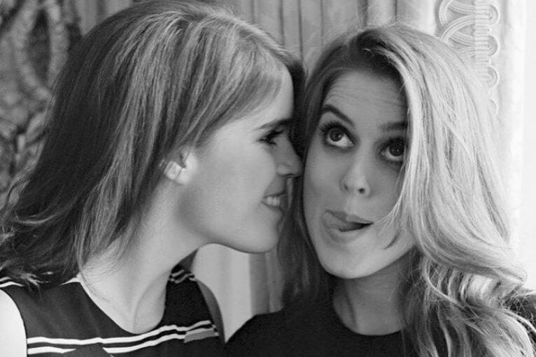 A black and white photo of Princess Beatrice and Eugenie pokinger her tongue out.