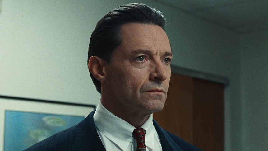 Still from the film Bad Education with Hugh Jackman in a suit looking concerned