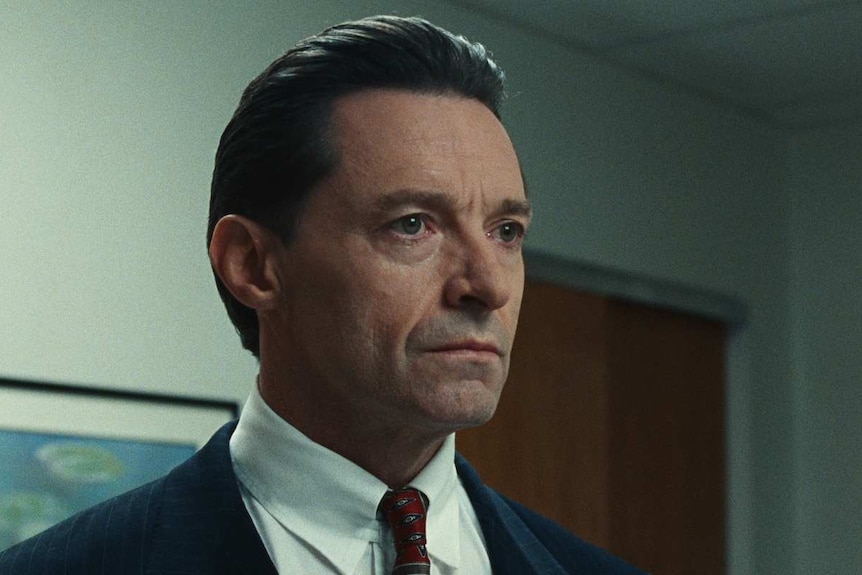 Still from the film Bad Education with Hugh Jackman in a suit looking concerned