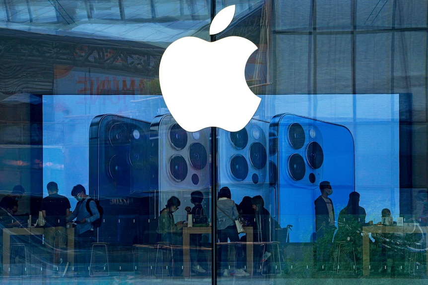人们戴着口罩在北京一家苹果专卖店试用最新款的iPhone手机。