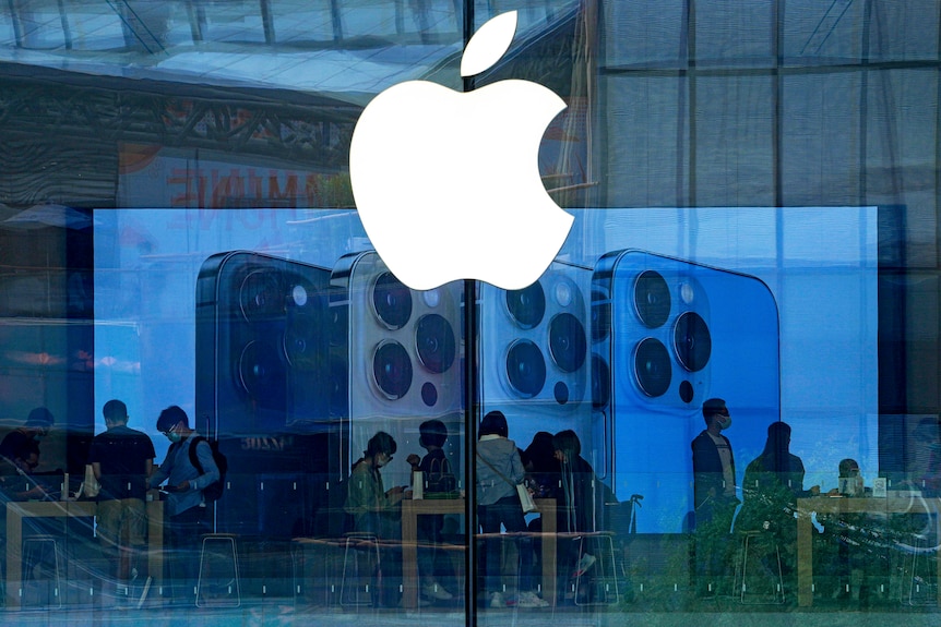 People wearing face masks try out the latest iPhone handsets at an Apple Store in Beijing.