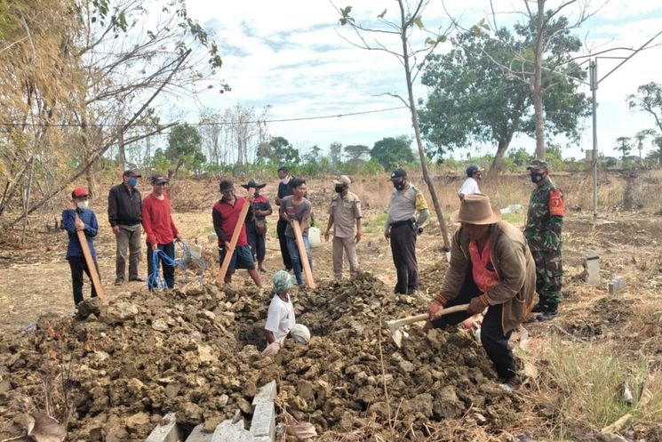 A group of people digging a land with a hoe during daylight time