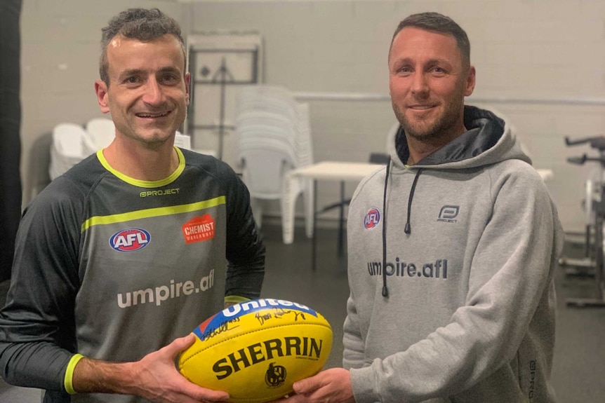 Boundary umpire Ian Burrows, left, is presented with the match ball by umpire Brett Rosebury.