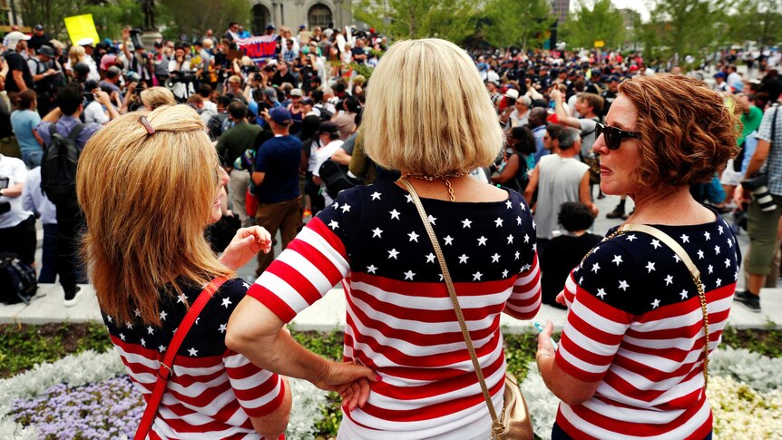 Women wearing US flag themed shirts watch demonstrators near the Republican National Convention in Cleveland, Ohio.