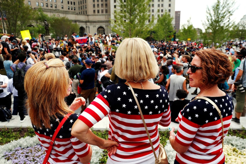 Women wearing US flag themed shirts watch demonstrators near the Republican National Convention in Cleveland, Ohio.