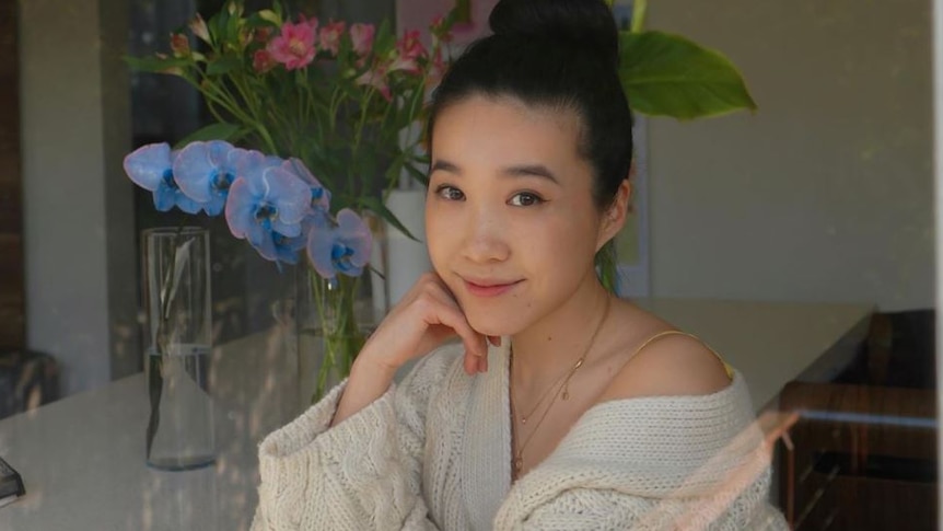 Jenny Zhou smiles calmly at the camera, resting her chin on her hand.