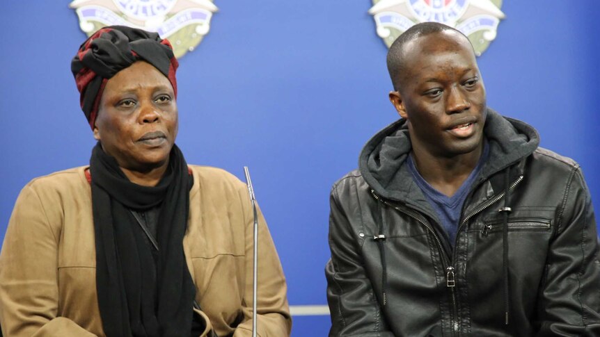 Yom Ayom and her son Emmanuel Arow sit side by in front of a Victoria Police backdrop.