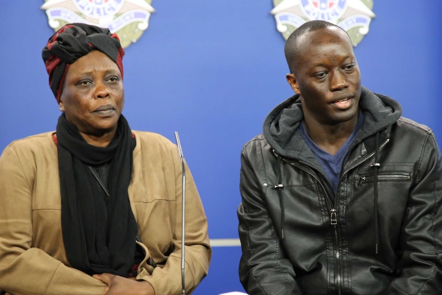 Yom Ayom and her son Emmanuel Arow sit side by in front of a Victoria Police backdrop.
