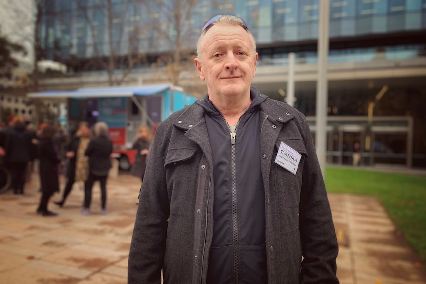 Man with grey hair wearing dark clothes smiles for the camera 