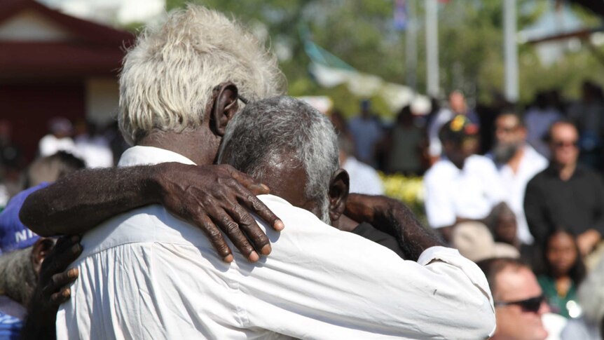 Two mourners hug at the funeral of Jack Long