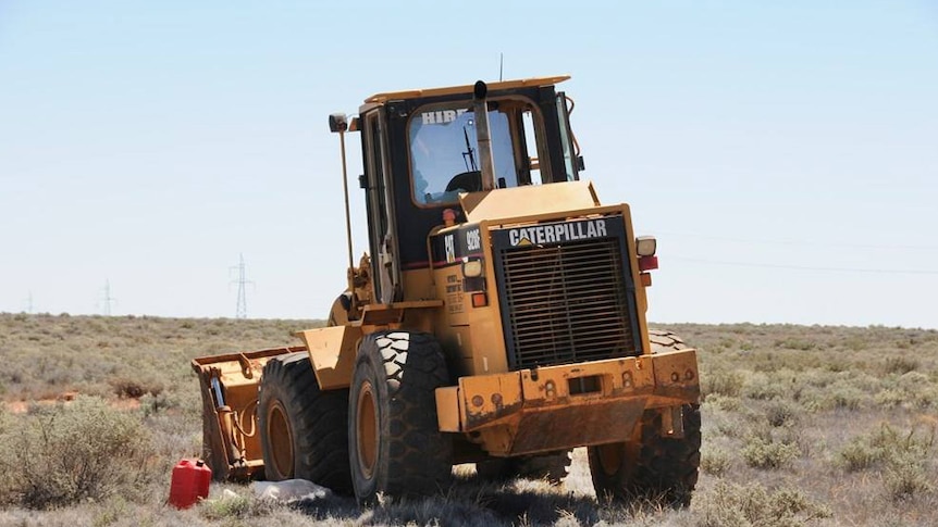 A front-end loader with bullet holes and smashed window
