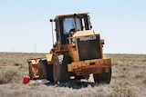 A front-end loader with bullet holes and smashed window