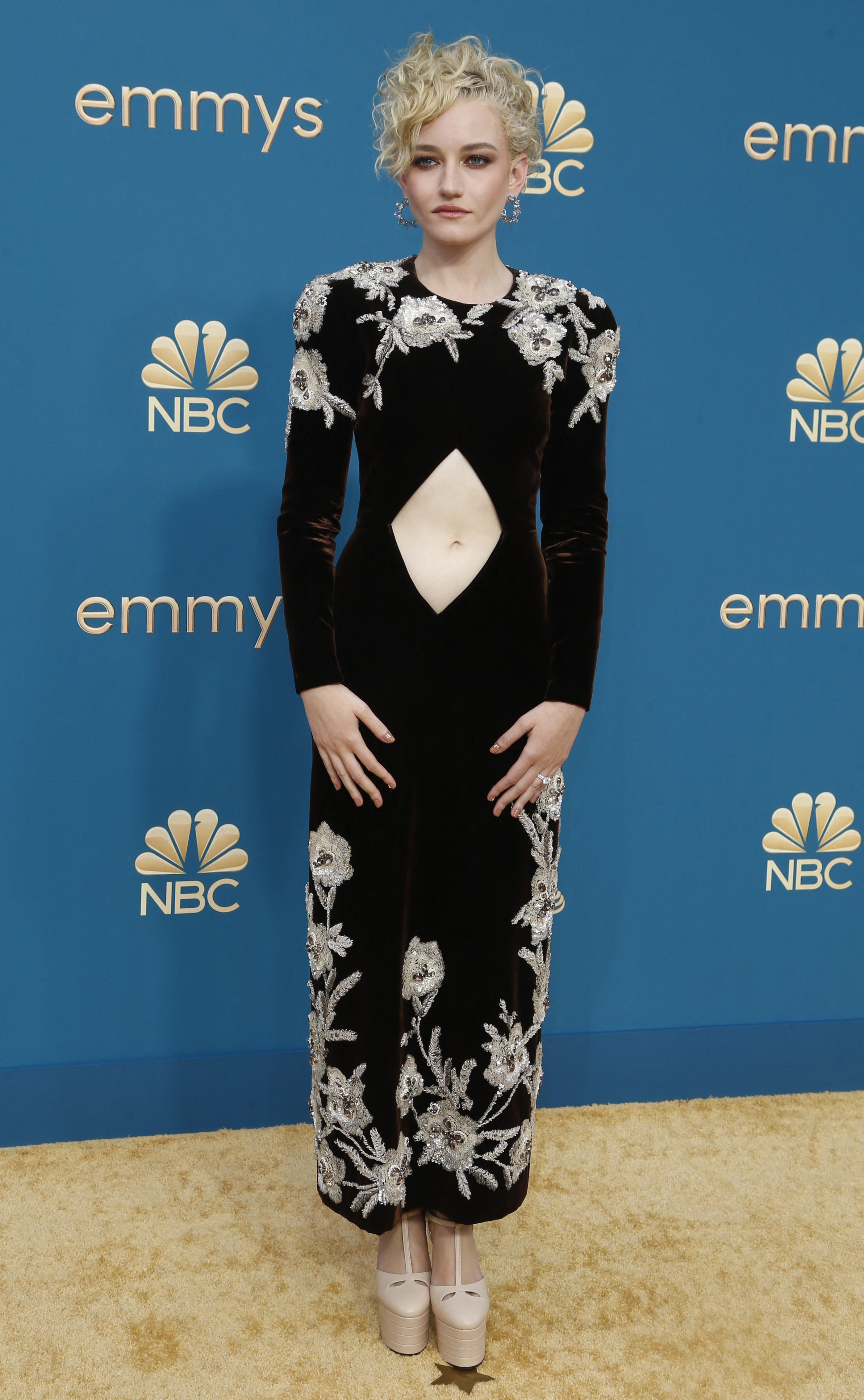 Julia Garner wearing a long-sleeve black gown with embellished flowers and a diamond-shaped cutout at the belly button