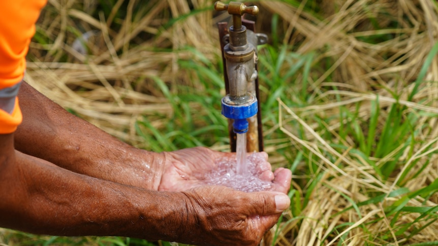 An Aboriginal man holds his hands under a tap