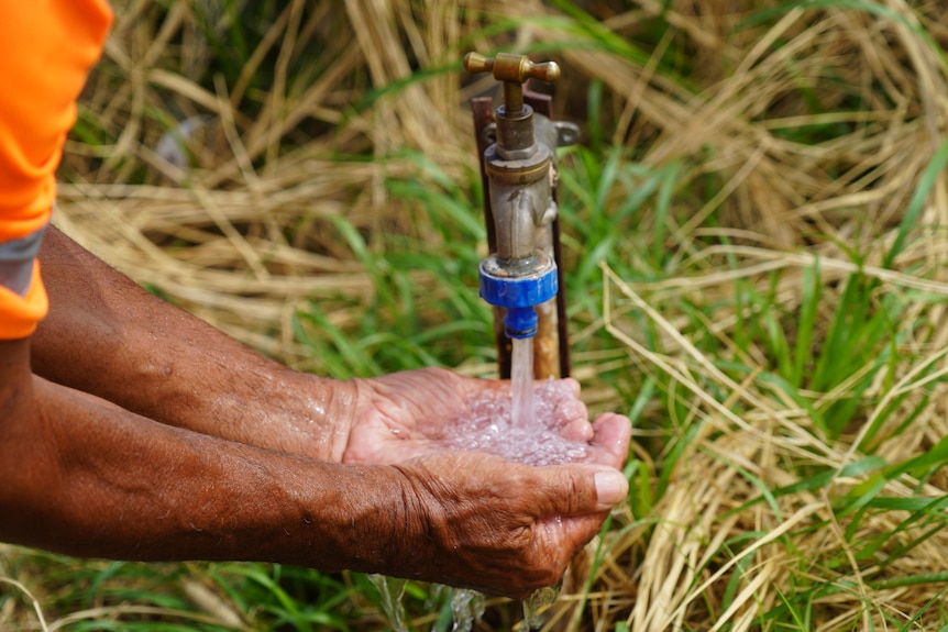 An Aboriginal man holds his hands under a tap