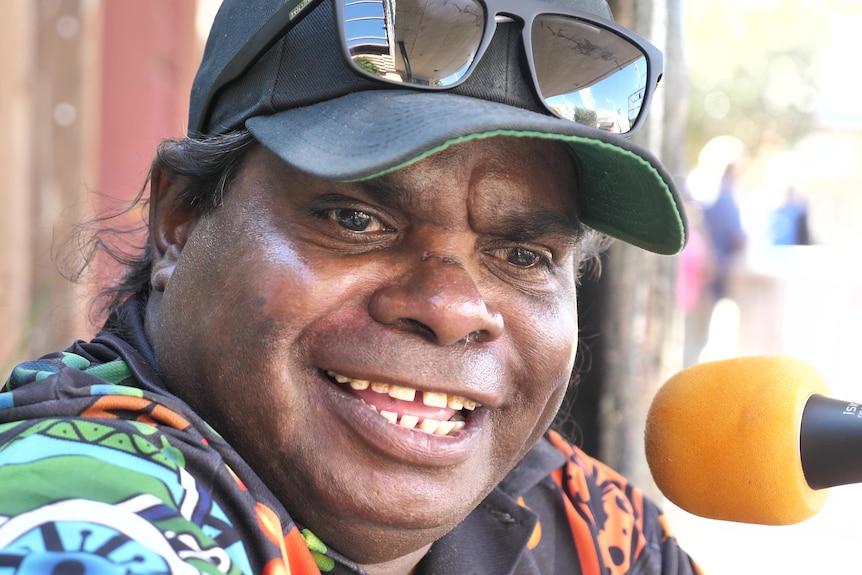 Close up photo of Indigenous man smiling in front of microphone.