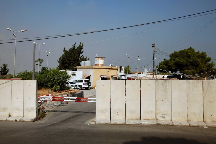 Cement walls and a red and white boom gate at the entrance to Roumieh prison in Beirut, Lebanon.